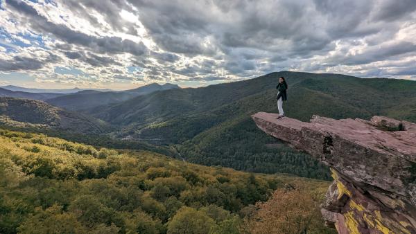 Foto de participante en una atalaya con vistas a valle con bosques.